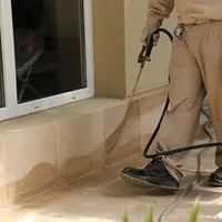 General pest control technician spraying exterior perimeter around a home in Charlotte, NC
