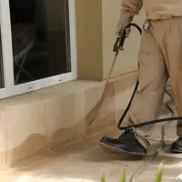 General pest control technician spraying exterior perimeter around a home in Charlotte, NC