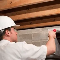 Termite inspection technician checking a basement wall and framing for termite activity in Charlotte, NC