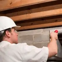 Termite inspection technician checking a basement wall and framing for termite activity in Charlotte, NC